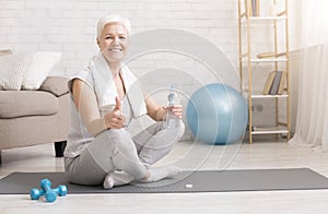Senior woman resting on exercise mat after fitness workout