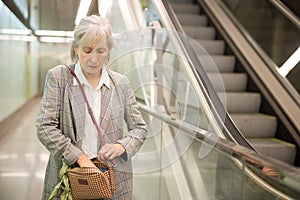 Senior woman rifling through her handbag in mall