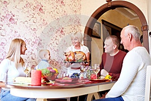 Senior woman with roasted turkey for a celebrating family on a light background. Tradition concept. Copy space.