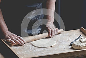 Senior woman roll fresh made pastry, preparing ingrediets for ho