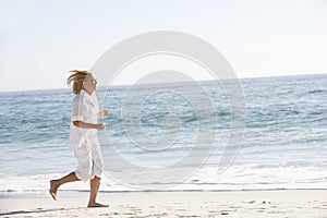 Senior Woman Running along Sandy Beach