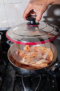 Senior woman& x27;s hand lifting a fancy holla lid to show the recipe for ready-to-cook chicken. Colombian cuisine.