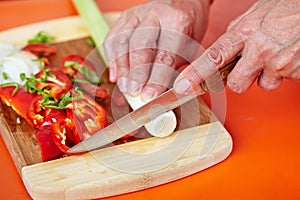 Senior woman's hands cutting vegetables