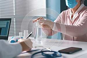 Senior woman sanitizing her hands at the doctor`s office