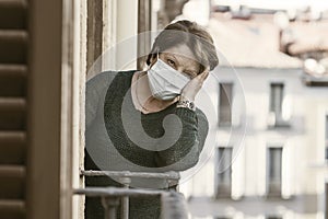 Senior woman scared and tired of covid19 - mature woman in protective mask stressed and worried at home balcony tired about home