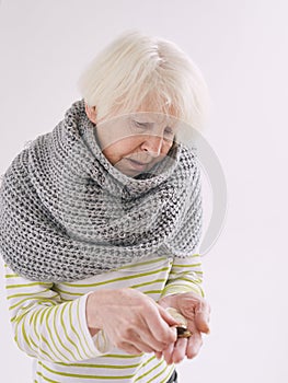 Senior woman in scarf counting coins.