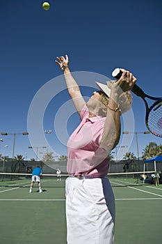 Senior Woman Serving Tennis Ball