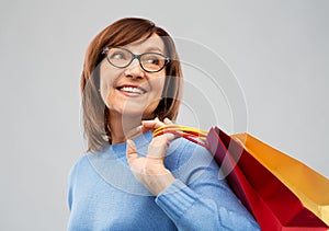 Senior woman with shopping bags over grey