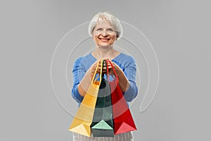 Senior woman with shopping bags over grey