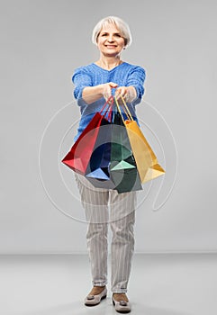 Senior woman with shopping bags over grey