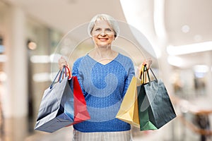 senior woman with shopping bags over grey