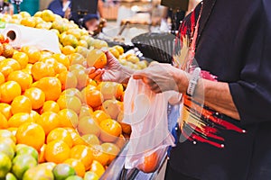 Senior woman shopping oranges at grocery store.