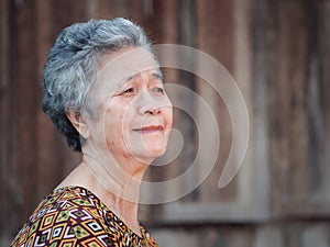 Senior woman with short gray hair, smiling and looking away while standing outdoors.