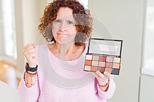 Senior woman showing nudes eyeshadows colors annoyed and frustrated shouting with anger, crazy and yelling with raised hand, anger