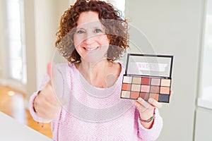 Senior woman showing nudes eyeshadows colors happy with big smile doing ok sign, thumb up with fingers, excellent sign