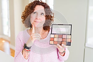 Senior woman showing nudes eyeshadows colors serious face thinking about question, very confused idea