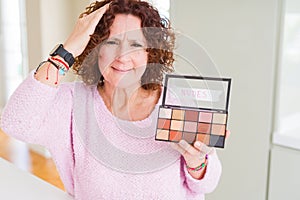 Senior woman showing nudes eyeshadows colors stressed with hand on head, shocked with shame and surprise face, angry and