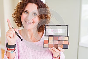 Senior woman showing nudes eyeshadows colors surprised with an idea or question pointing finger with happy face, number one