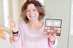 Senior woman showing nudes eyeshadows colors very happy pointing with hand and finger to the side