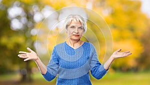 Senior woman shrugging in autumn park