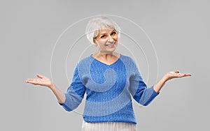 Senior woman shrugging or presenting something