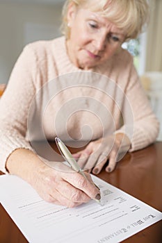 Senior Woman Signing Last Will And Testament At Home