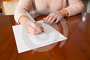 Senior Woman Signing Last Will And Testament At Home