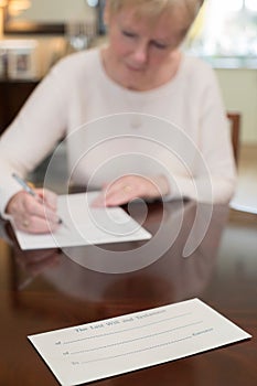 Senior Woman Signing Last Will And Testament At Home