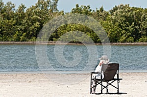 Senior woman siting in beach chair relaxing on a tropical beach
