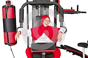 Senior woman sits on gym equipment after workout