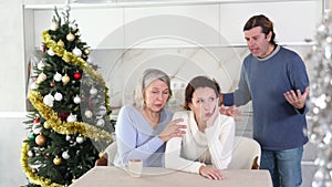 Senior woman sits near daughter and comforts during quarrel with husband on Christmas Eve