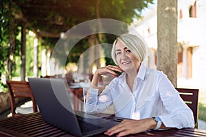 Senior woman sitting at a cafe with laptop computer