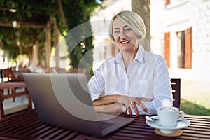 Senior woman sitting at a cafe with laptop computer