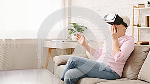 Senior Woman Sitting on Couch Wearing Virtual Reality Headset