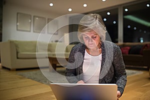 Senior woman sitting on the floor working on laptop