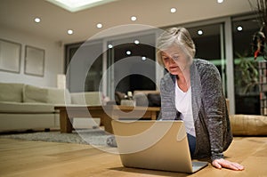 Senior woman sitting on the floor working on laptop