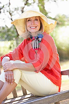 Senior Woman Sitting Outdoors On Bench