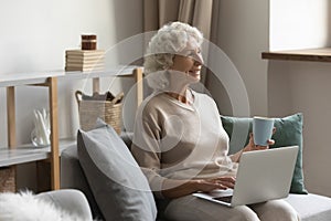 Senior woman sitting on sofa, enjoying morning time.