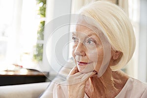 Senior Woman Sitting On Sofa At Home Suffering From Depression