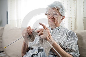Senior woman sitting on a sofa and knitting