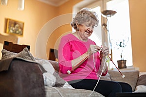 Senior woman sitting on sofa knitting