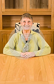 Senior woman sitting at table with copyspace below