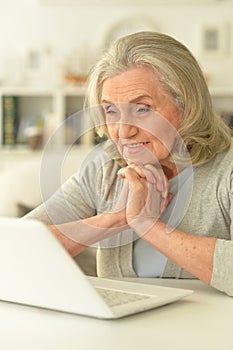 Senior woman sitting at table with laptop