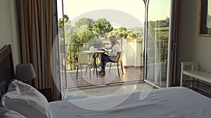 Senior woman sitting on the terrace of her hotel reading a book and enjoying the good weather.