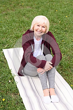 senior woman sitting on yoga mat