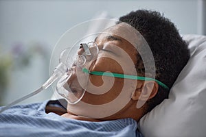Senior woman sleeping on bed in hospital with oxygen support mask