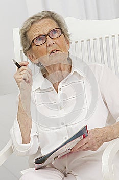 Senior woman sloving crosswords on a magazine photo