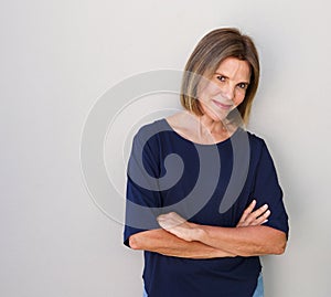 Senior woman smiling against gray wall