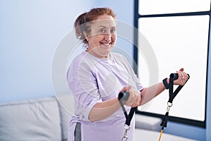 Senior woman smiling confident using elastic band training at home