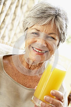 Senior Woman Smiling And Drinking Orange Juice